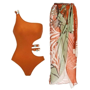 Detail of beaded texture on one-shoulder orange swimsuit with tropical leaf sarong