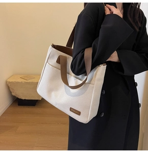 Detail of canvas tote bag with brown straps and contrast stitching for daily commute
