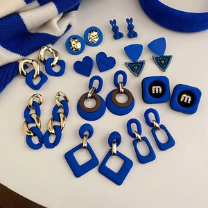 Close-up of Klein Blue earrings set featuring geometric heart and chain designs with gold finish