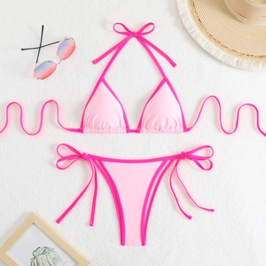 Flat lay of pink color-block bikini with string tie details on a white plush rug