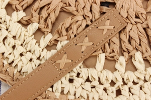 Detailed macro shot of hand-woven straw texture and brown leather strap with X-stitching