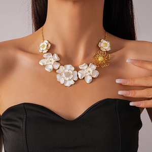 Close-up of white enamel flower necklace with crystal center and gold details