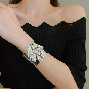 Detailed view of wide silver metal cuff bracelet featuring a 3D flower and center pearl