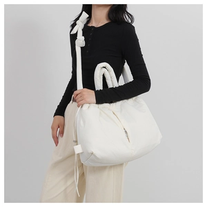 Chic cream nylon padded tote bag with drawstring closure worn by model on shoulder