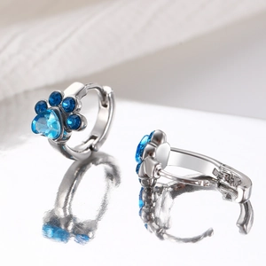 Detalle de pendientes de huella de gato en plata con circón azul de corazón