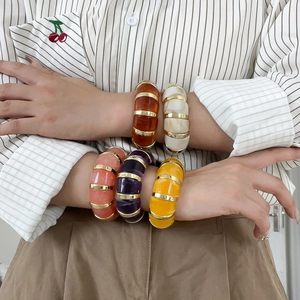 Bracelets géométriques rétro en résine multicolore avec accents dorés portés au poignet