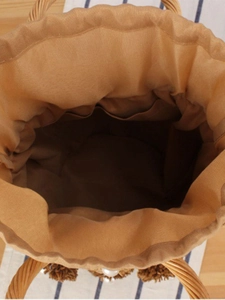 Handmade woven bucket bag with pearl details and brown tassels in a top-view layout