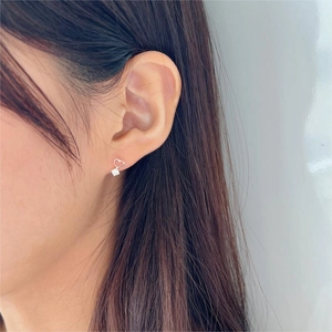 Detail view of heart-shaped silver stud earring with zircon stone on model ear