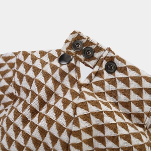 Macro shot of geometric triangle embroidery and metal snap buttons on woven fabric
