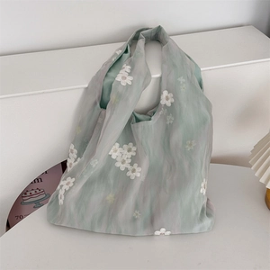 Detailed close-up of light mint green organza bag with delicate white daisy embroidery