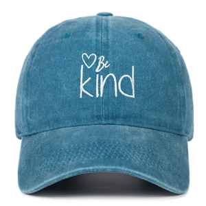Close-up of Be Kind embroidery and heart pattern on blue washed denim baseball cap