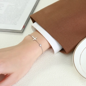 Close-up of minimalist silver stainless steel cross bracelet with zircon on wrist