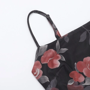 Détail des fines bretelles réglables et du tissu en tulle fleuri sur une robe noire