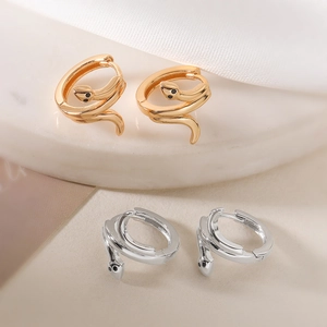 Minimalist 18K gold and silver snake hoop earrings displayed on white marble