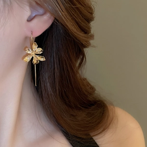 Close-up of elegant gold iris flower earrings on model with long dangle design