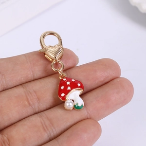 Detail of red mushroom pendant with white spots, pearl accent and gold lobster clasp