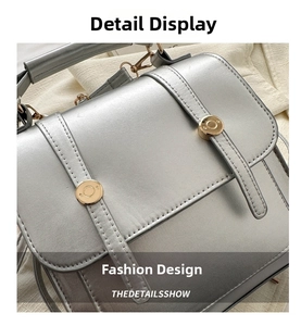 Détail du sac à main en cuir argenté avec texture fine et boucles métalliques dorées