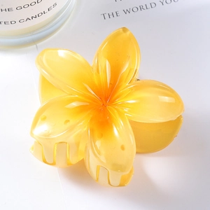 Detailed macro view of high-gloss yellow resin plumeria flower hair claw clip