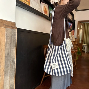 Detail of blue striped canvas tote bag with white lace trim and brand logo label
