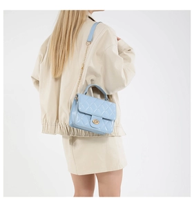 Close-up of a light blue quilted crossbody bag with a golden chain strap and metal lock