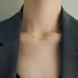 Dettaglio di una collana a catena dorata in acciaio inossidabile indossata da una modella