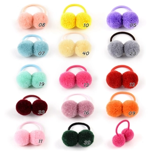 Flat lay matrix of colorful plush pom pom hair ties on white background for girls