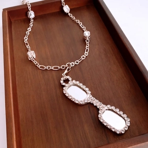 Square eyewear pendant necklace with Figaro chain and zircon accents on wood background
