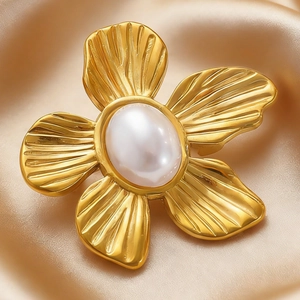 Detailed close-up of a golden flower brooch with a large white pearl on silk fabric