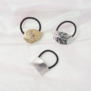 Minimalist metallic hair ties set with gold leaf and silver feather charms on silk