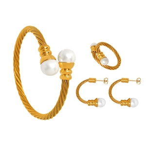 Golden woven jewelry set featuring pearl bracelet, ring, and earrings on white background