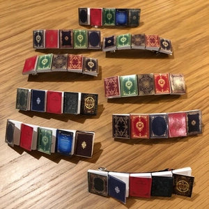 Miniature book hair clips with vintage covers on a rustic wooden background