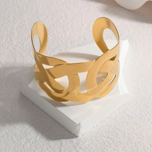 Modern wide hollow interlocking gold cuff bracelet on minimalist white stone base
