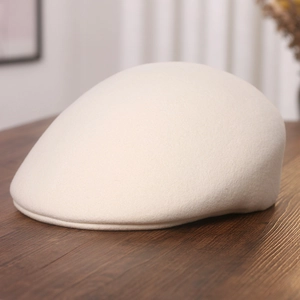 Classic beige wool felt beret hat for women on wooden surface for autumn and winter