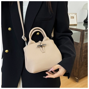 Detail of beige bucket bag with bamboo metal clasp and litchi grain leather texture