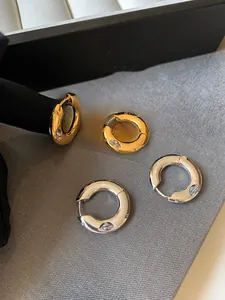 Detailed shot of gold and silver hoop earrings with marquise-cut zircon stones on fabric