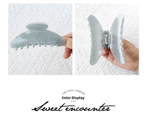 Detail of light blue glitter acrylic hair claw clips in butterfly and crescent shapes