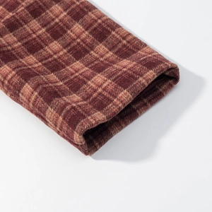 Detail of classic plaid wool blend coat showing red-brown fabric texture and cuff stitching
