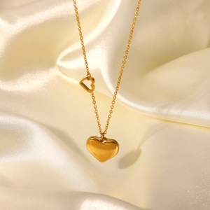 Detail of 18K gold-plated double heart pendant necklace on elegant beige silk background