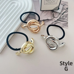 Detailed view of elastic hair ties featuring textured gold, silver, and bronze metal knots