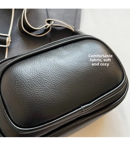 Close-up of black lychee grain leather texture and metallic buckle on small round bag