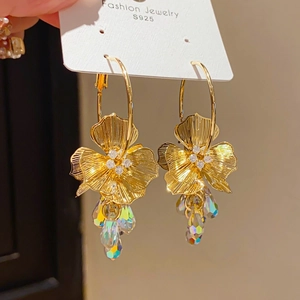 Macro shot of gold floral earrings with crystal fringe and sparkling zircon details