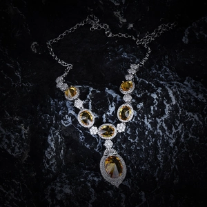 Detailed view of luxury yellow oval gemstones and zircons on a silver-toned necklace