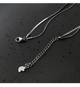 Close-up of silver snake chain necklace featuring a lobster clasp and elephant charm detail