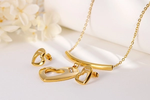 Detail of gold heart necklace and earrings set with shimmering crystals on a white background