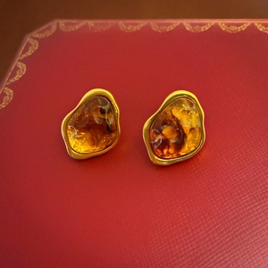 Close-up of vintage resin earrings with gold edges on a red luxury gift box top
