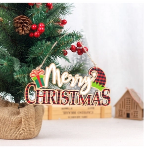 Detail of wooden Merry Christmas hanging sign with red plaid pattern on a mini tree