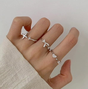 Close-up of three silver open rings featuring star, bow, and arrow heart designs with zircons