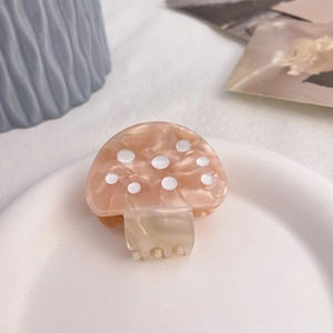 Nahaufnahme einer Haarspange aus rosa Acetat in Pilzform auf einer Keramikschale