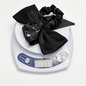 Bow hair scrunchie with skull pattern on a digital scale showing weight of 17.7g