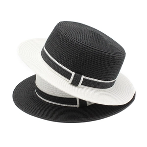 Detail view of two-tone woven straw hats with contrast ribbon bows and flat crowns